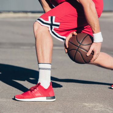Ausgeschnittenes Bild eines Basketballspielers, der auf der Straße Basketball spielt.